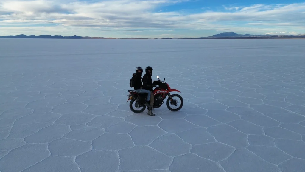Moto roulant sur l'immensité blanche du Salar de Uyuni, Bolivie