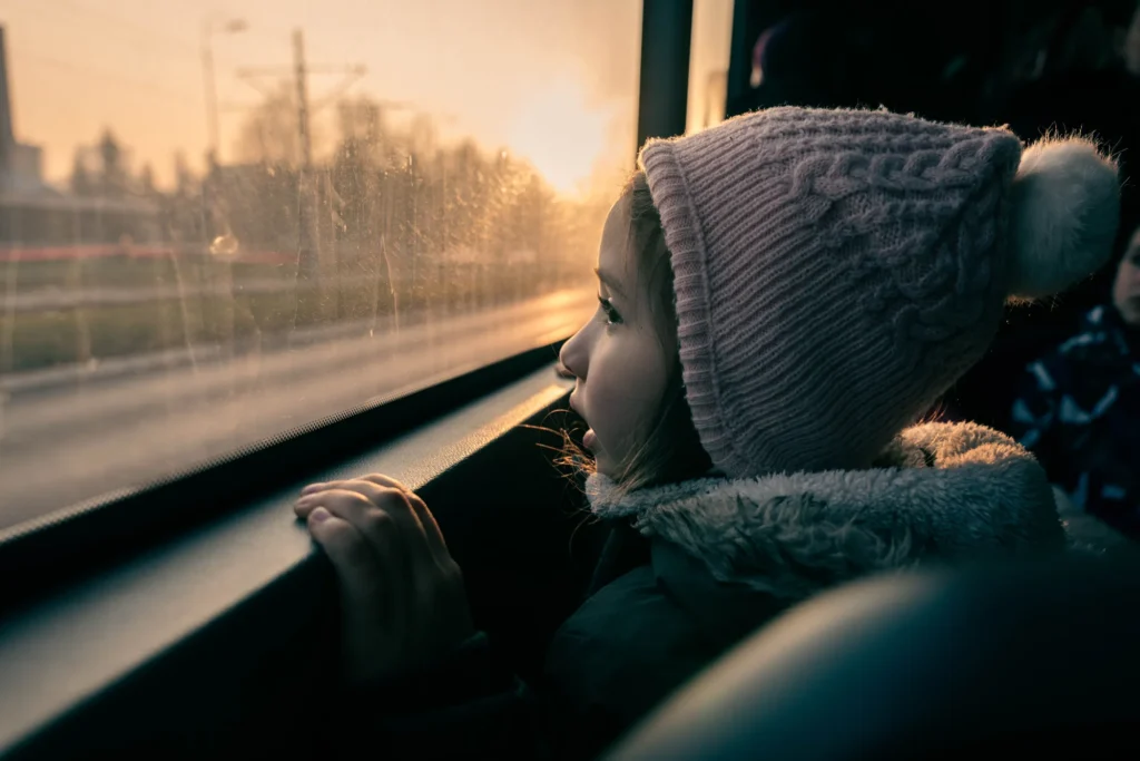 Une petite fille regarde le paysage par la fenêtre d'un train au coucher du soleil